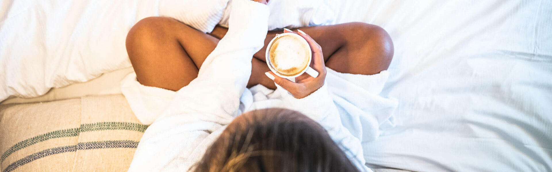 Frau trinkt einen Cafe im Hotelbett