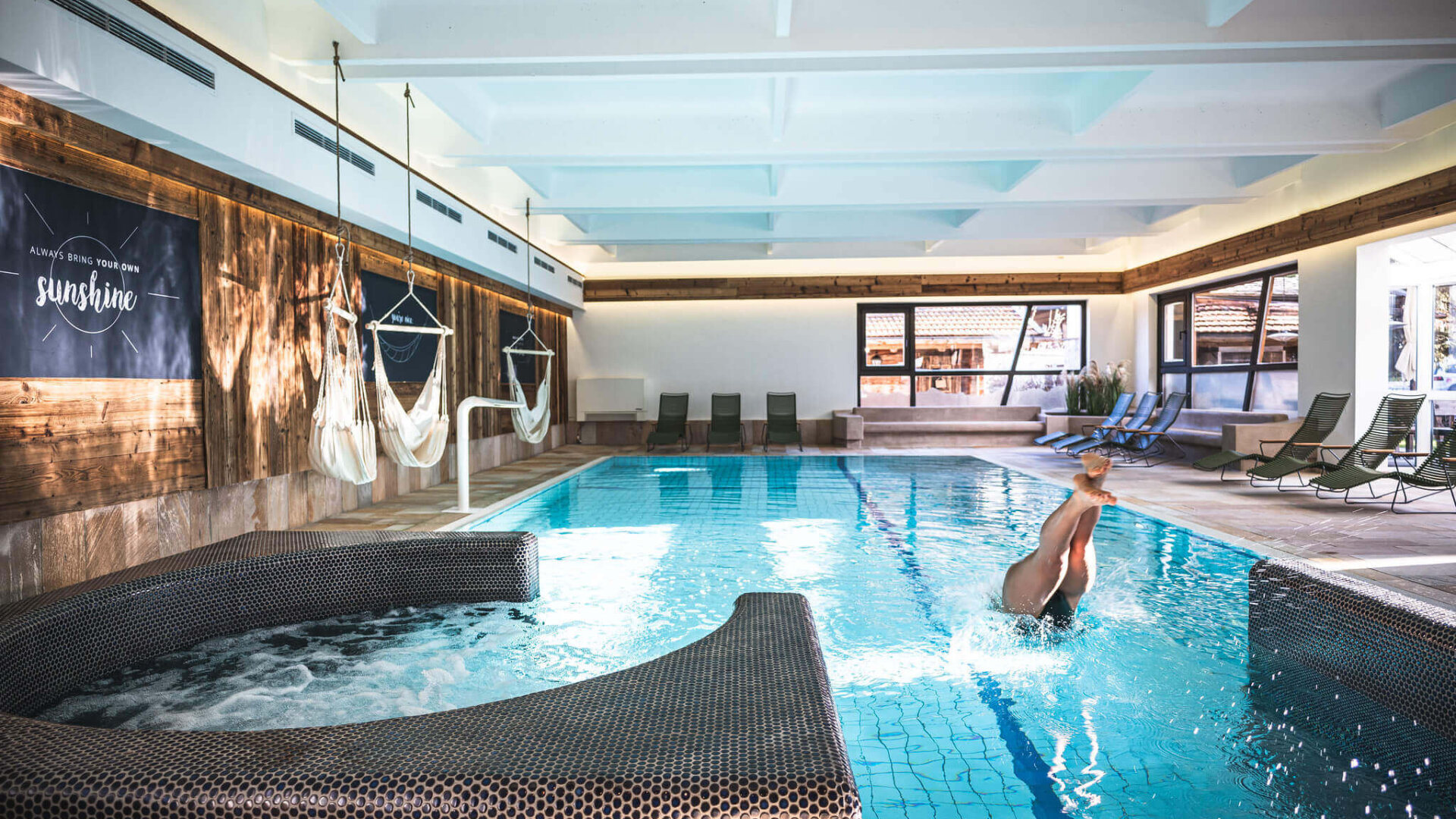 Frau springt ins Hallenbad im Wellnessbereich