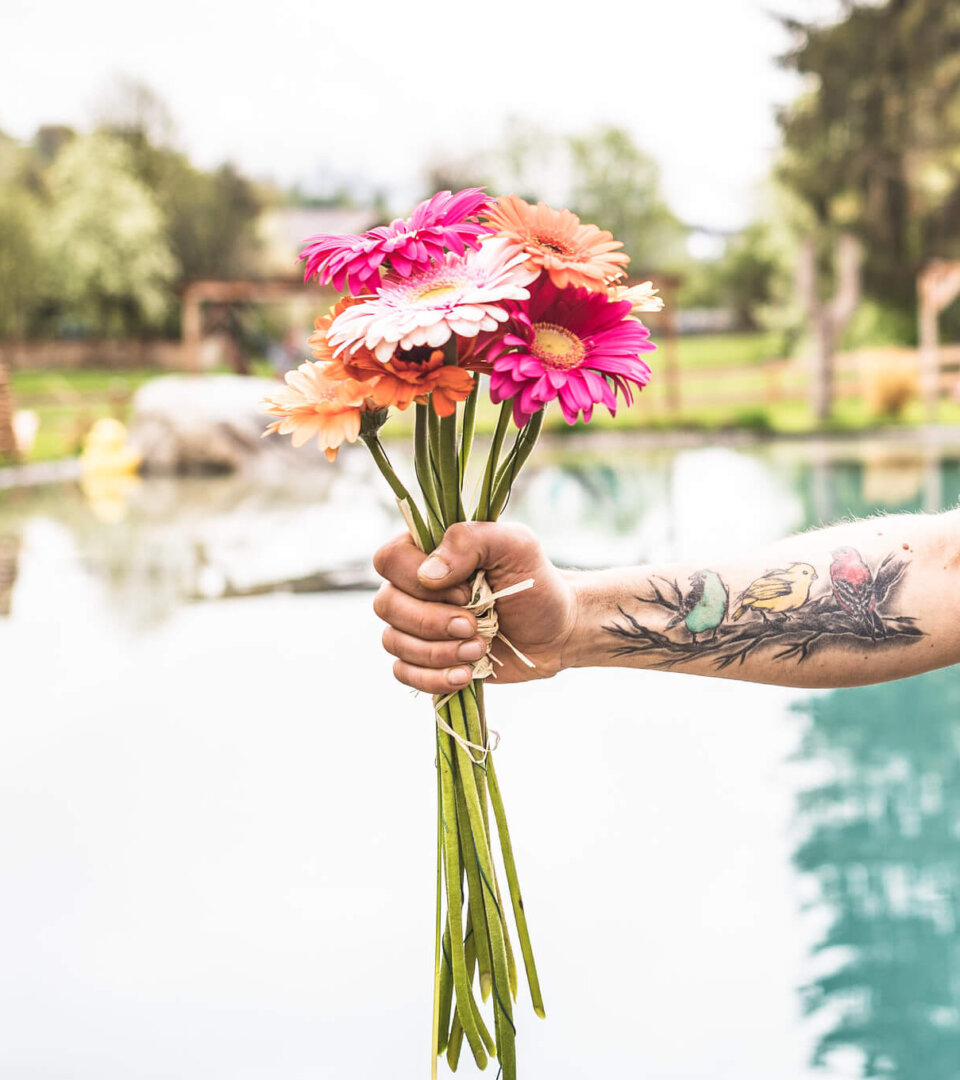 Tätowierte Hand hält einen bunten Blumenstrauß