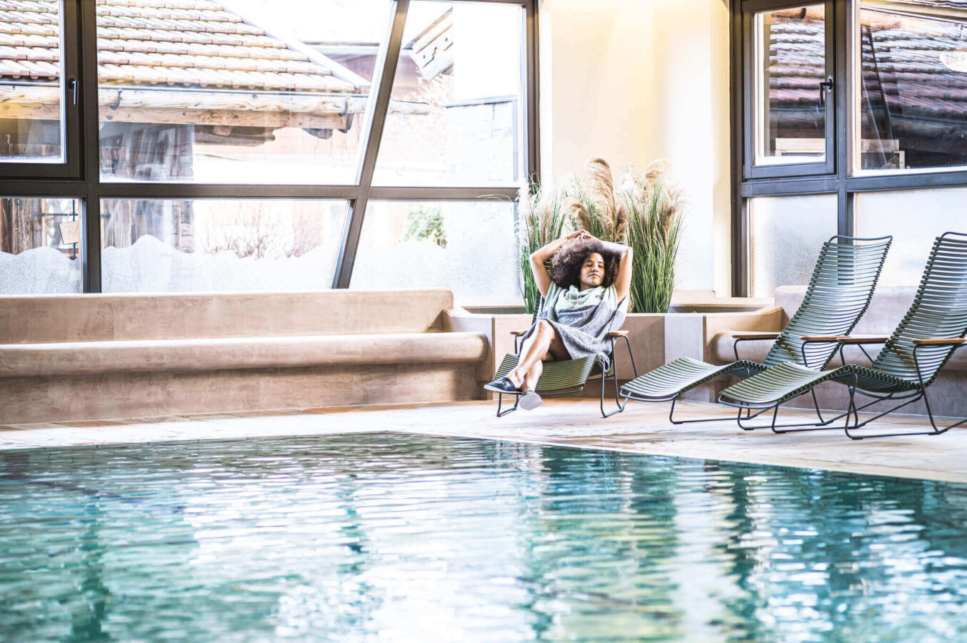 Frau relaxed auf Liegestuhl am Wasser im Hallenbad