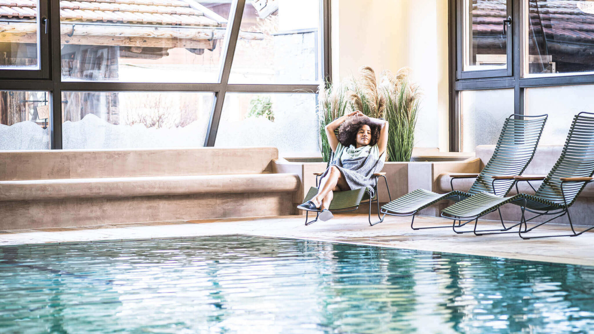 Frau relaxed auf Liegestuhl am Wasser im Hallenbad