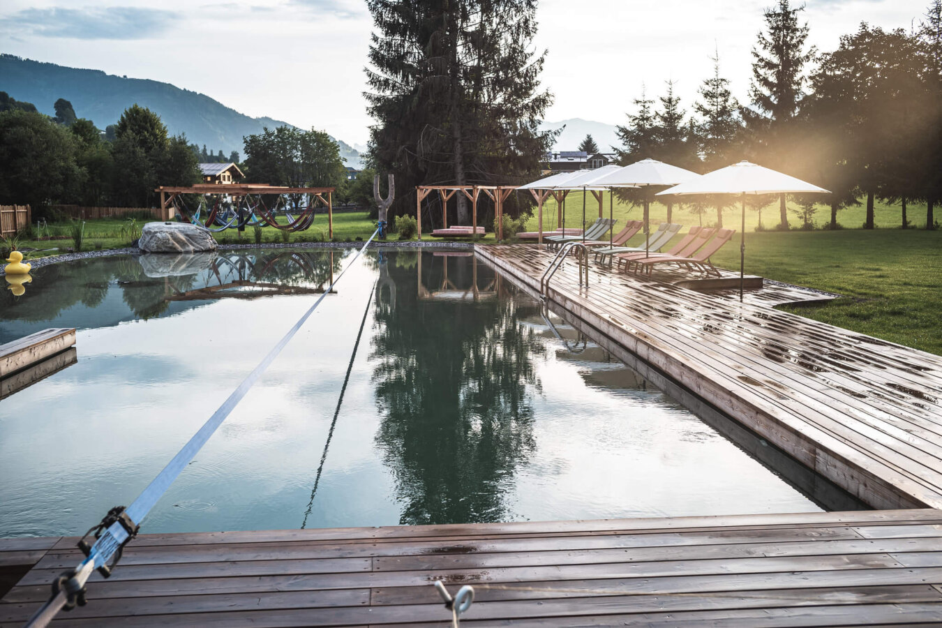 Naturschwimmteich mit Slakeline mit Aussicht auf die Berge