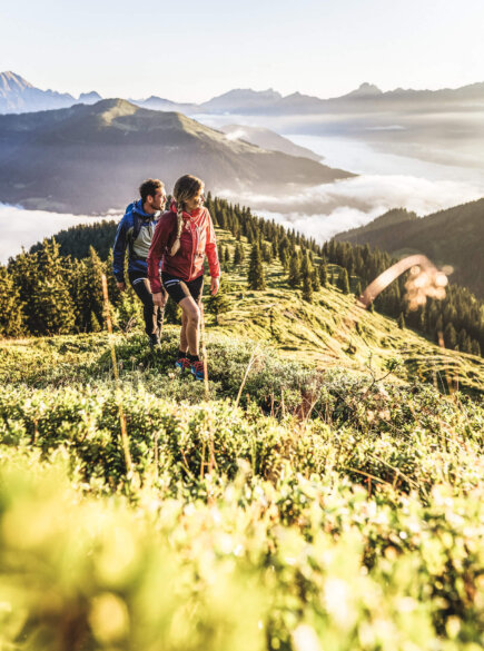 Ein Paar wandert in Zell am See. Im Hintergrund eine wunderschöne Bergkulisse